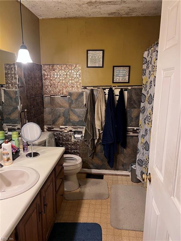 bathroom featuring vanity, toilet, and tile walls