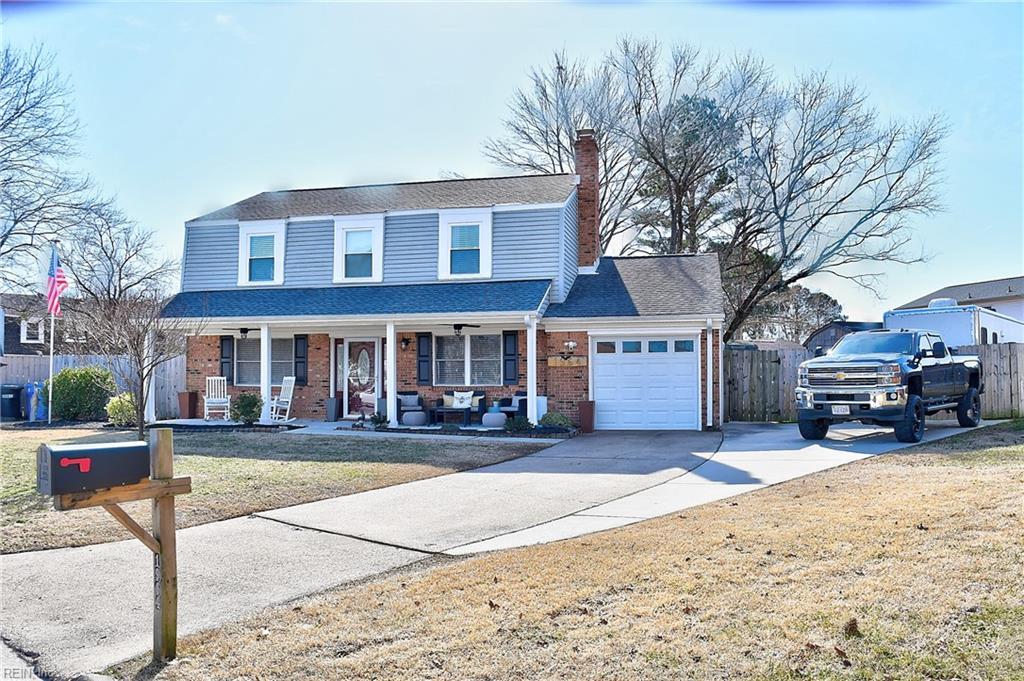 view of property featuring a garage, a front yard, and covered porch