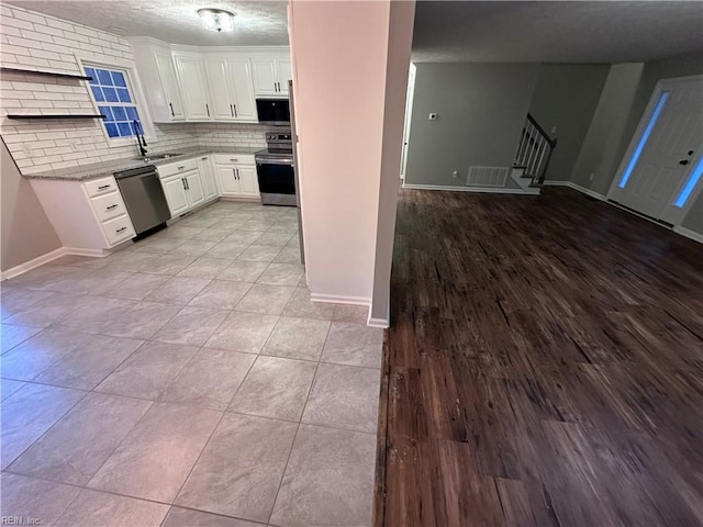 kitchen with tasteful backsplash, sink, white cabinets, light stone counters, and stainless steel appliances