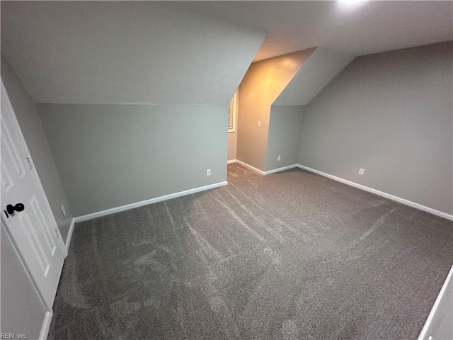 additional living space with vaulted ceiling and dark colored carpet