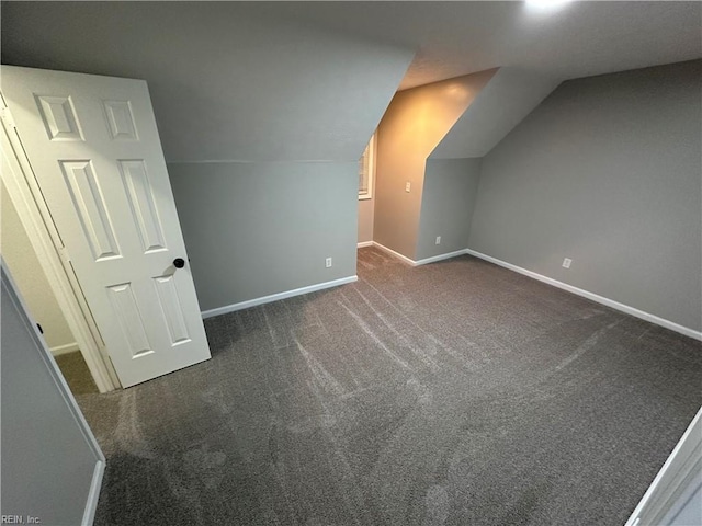 additional living space featuring dark colored carpet and lofted ceiling