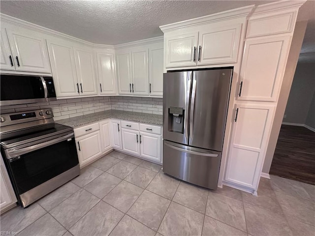 kitchen with white cabinetry, appliances with stainless steel finishes, light stone countertops, and light tile patterned flooring