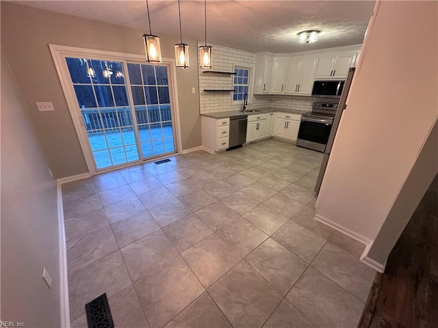 kitchen with pendant lighting, sink, white cabinets, decorative backsplash, and stainless steel appliances