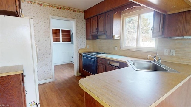 kitchen with sink, kitchen peninsula, gas stove, and white fridge