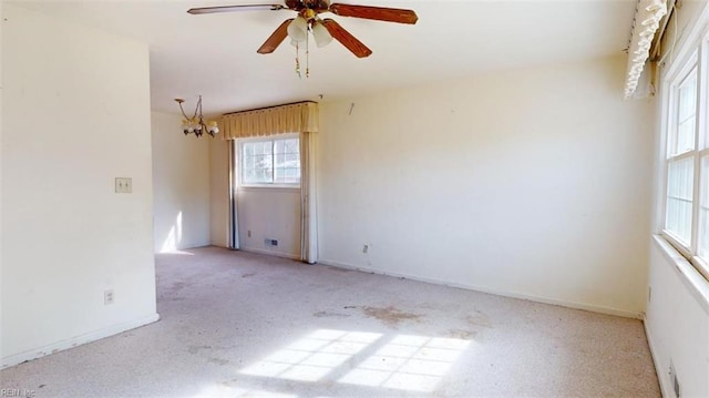 unfurnished room with ceiling fan with notable chandelier