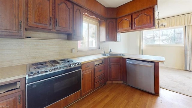 kitchen with sink, stainless steel appliances, tasteful backsplash, light hardwood / wood-style floors, and kitchen peninsula