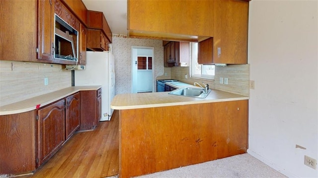 kitchen featuring sink, range, white refrigerator, decorative backsplash, and kitchen peninsula