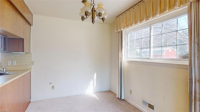 interior space featuring light carpet, sink, and a chandelier