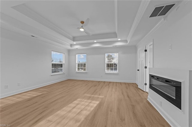 unfurnished living room featuring a raised ceiling, crown molding, ceiling fan, and light wood-type flooring