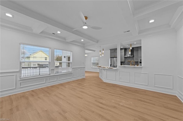 unfurnished living room with crown molding, ceiling fan, beam ceiling, coffered ceiling, and light hardwood / wood-style floors