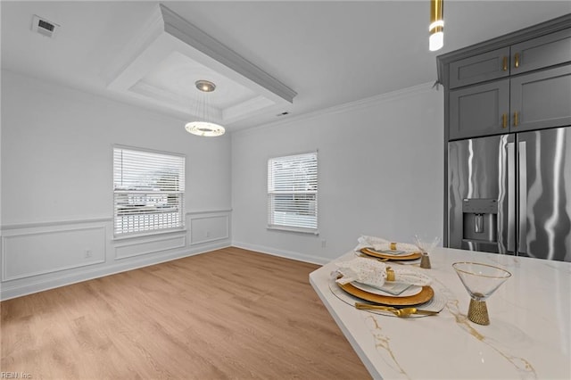 unfurnished dining area with crown molding, a raised ceiling, light hardwood / wood-style flooring, and a wealth of natural light