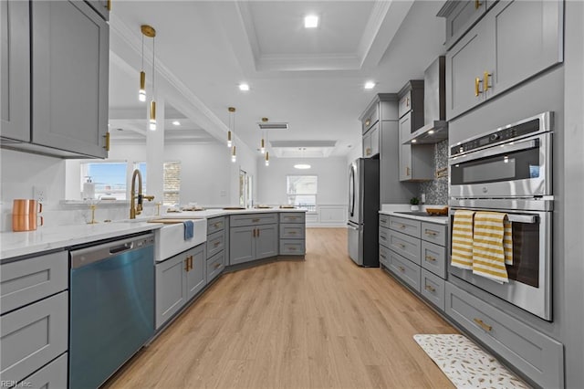 kitchen with gray cabinetry, pendant lighting, a raised ceiling, and appliances with stainless steel finishes