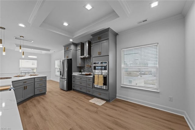 kitchen with wall chimney exhaust hood, decorative light fixtures, gray cabinets, stainless steel appliances, and light hardwood / wood-style floors