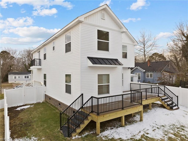 snow covered back of property featuring a wooden deck