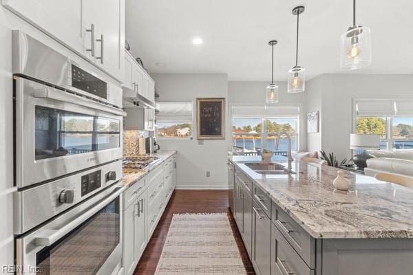 kitchen with sink, white cabinetry, an island with sink, pendant lighting, and stainless steel appliances