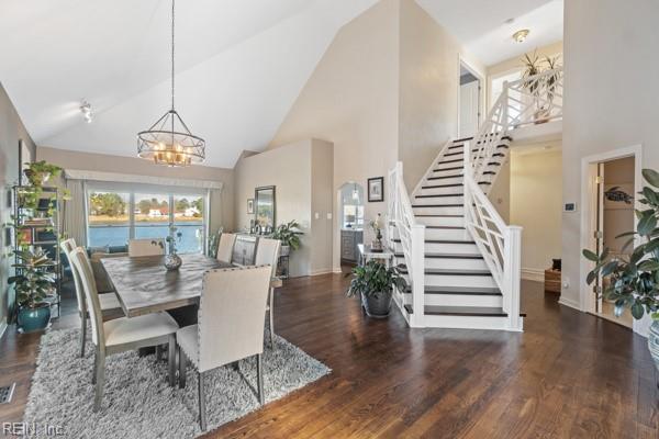 dining room with dark wood-type flooring, a chandelier, and high vaulted ceiling