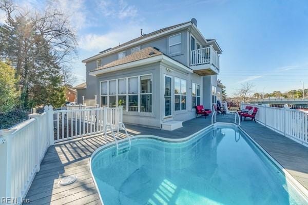 rear view of house with a balcony and a swimming pool side deck