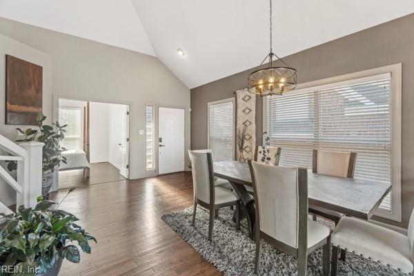 dining space with dark hardwood / wood-style flooring, a chandelier, and high vaulted ceiling