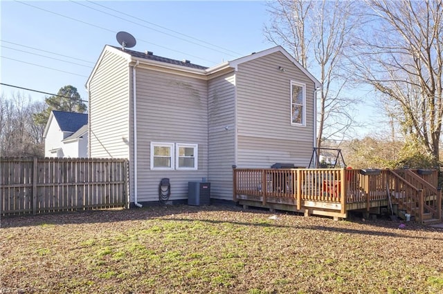 rear view of house featuring a lawn, central air condition unit, and a deck