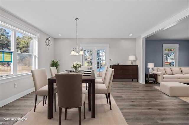 dining area featuring a healthy amount of sunlight, hardwood / wood-style floors, and an inviting chandelier