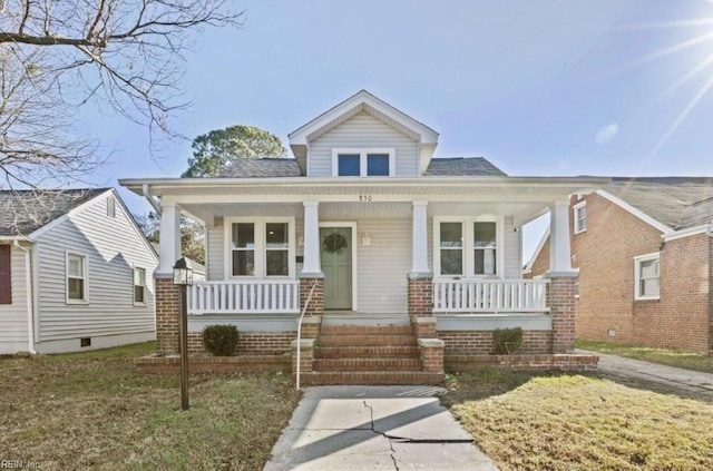 bungalow-style home featuring covered porch and a front lawn