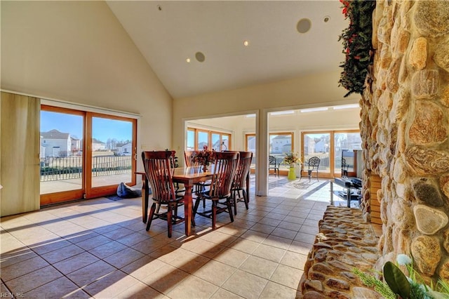 dining room featuring a healthy amount of sunlight, light tile patterned floors, and high vaulted ceiling