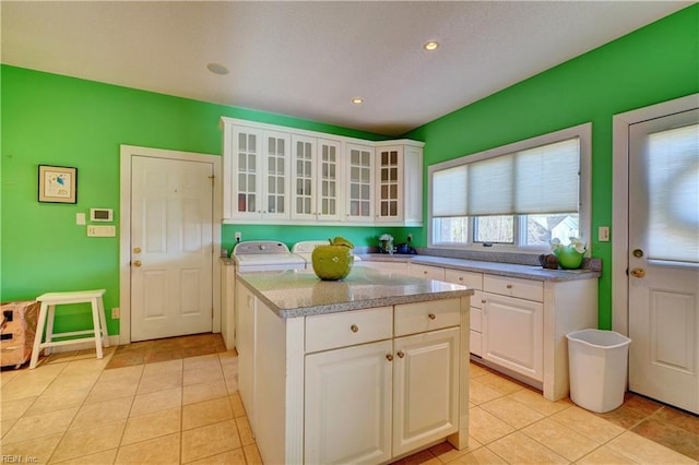 kitchen featuring white cabinetry, light tile patterned floors, light stone counters, and a kitchen island