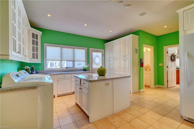 kitchen with sink, white cabinetry, washer and dryer, white refrigerator, and a kitchen island