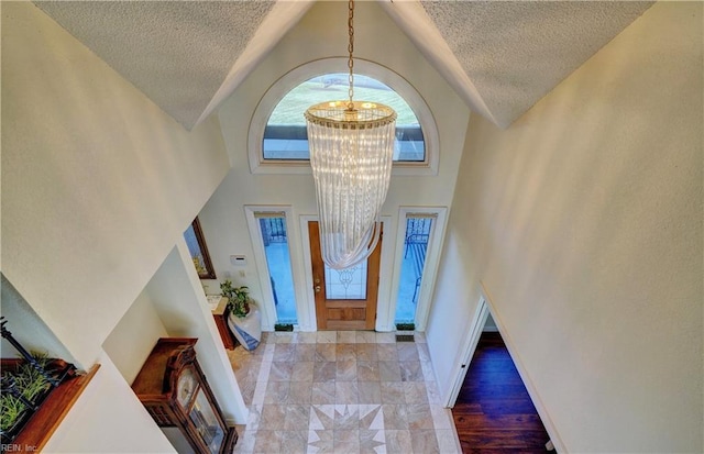 foyer entrance with a high ceiling, a notable chandelier, and a textured ceiling