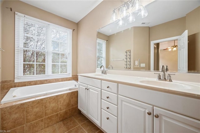 bathroom with tile patterned flooring, vanity, and tiled bath