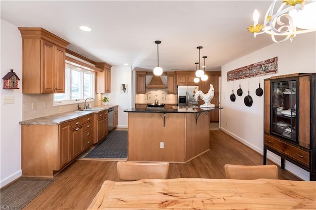 kitchen featuring sink, dark hardwood / wood-style flooring, pendant lighting, stainless steel appliances, and wall chimney range hood