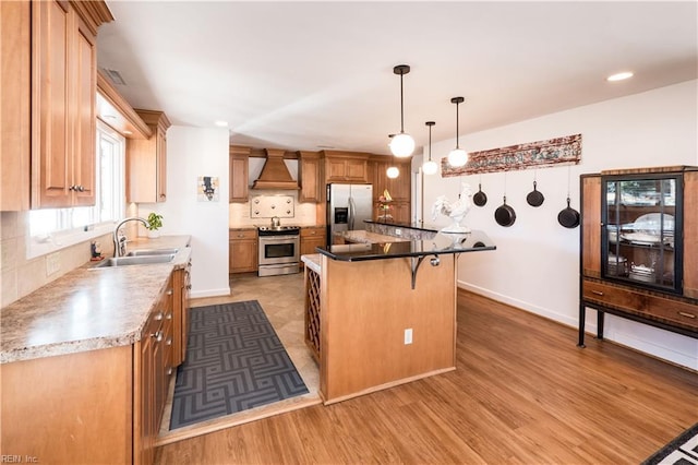 kitchen featuring sink, custom exhaust hood, light wood-type flooring, a kitchen island, and stainless steel appliances