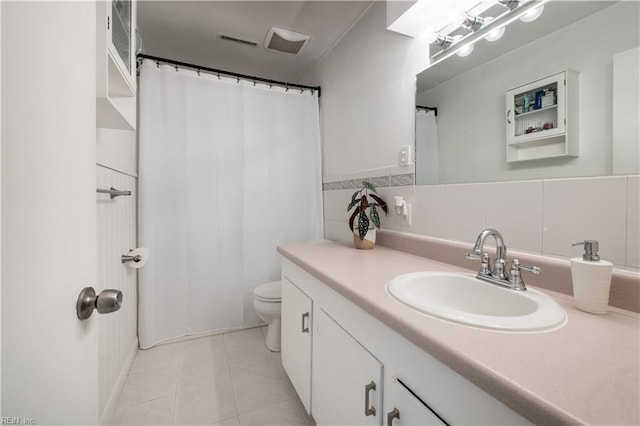 bathroom with tile patterned flooring, vanity, tile walls, and toilet