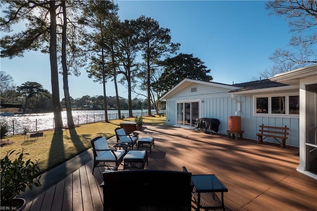 deck with a water view and a lawn