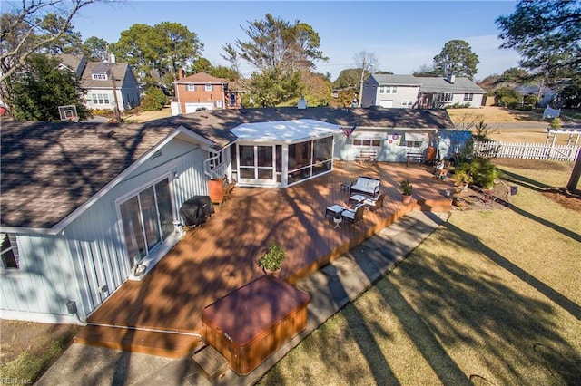 back of property with a wooden deck, a yard, and a sunroom