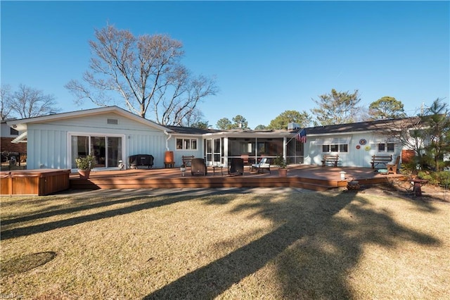 rear view of property featuring a lawn, a hot tub, a sunroom, and a deck