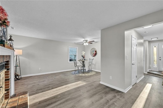 workout area featuring dark hardwood / wood-style flooring, a textured ceiling, a fireplace, and ceiling fan