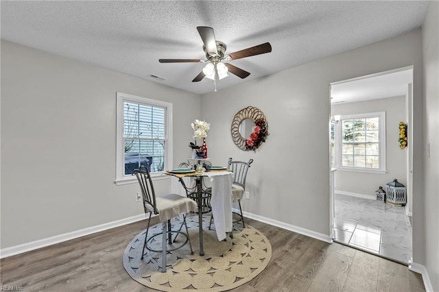 dining area with ceiling fan, dark hardwood / wood-style flooring, and a textured ceiling