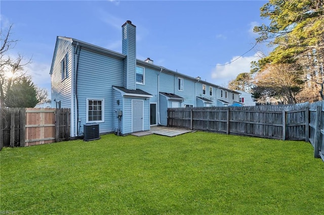 back of house with central AC unit and a lawn