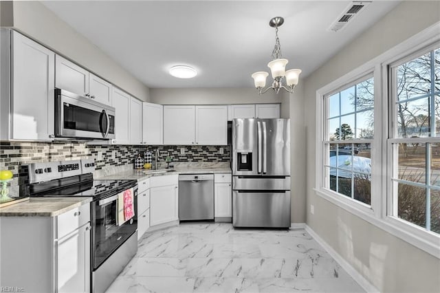 kitchen featuring stainless steel appliances, white cabinetry, decorative backsplash, and decorative light fixtures