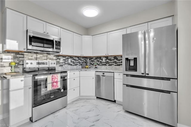 kitchen featuring tasteful backsplash, white cabinetry, appliances with stainless steel finishes, and light stone countertops