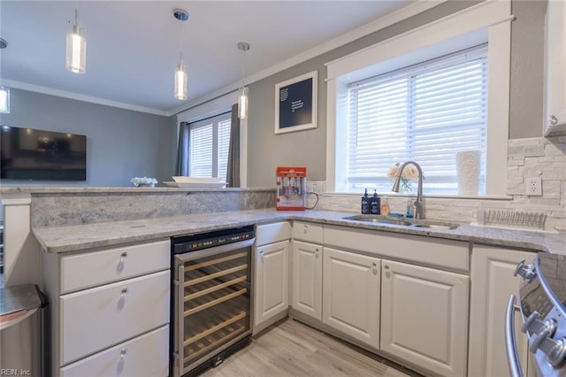 kitchen with stainless steel stove, decorative light fixtures, white cabinetry, sink, and beverage cooler