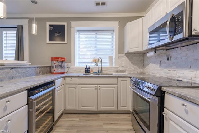 kitchen with sink, white cabinets, beverage cooler, stainless steel appliances, and crown molding