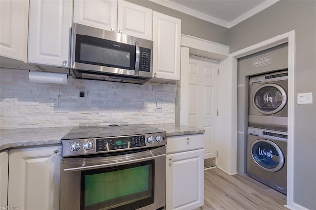 kitchen featuring stacked washer and clothes dryer, crown molding, tasteful backsplash, appliances with stainless steel finishes, and white cabinets