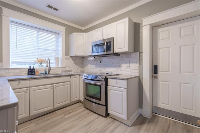 kitchen with sink, appliances with stainless steel finishes, light stone countertops, decorative backsplash, and white cabinets