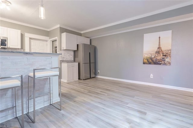 kitchen with white cabinetry, ornamental molding, appliances with stainless steel finishes, and backsplash