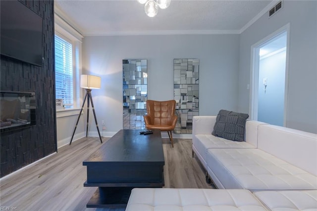 living room featuring a large fireplace, ornamental molding, and hardwood / wood-style floors