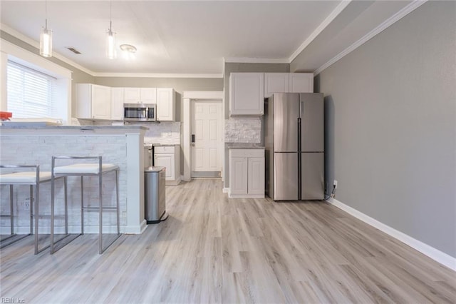 kitchen with tasteful backsplash, appliances with stainless steel finishes, decorative light fixtures, and white cabinets