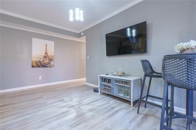 living room with crown molding, an inviting chandelier, and light hardwood / wood-style flooring