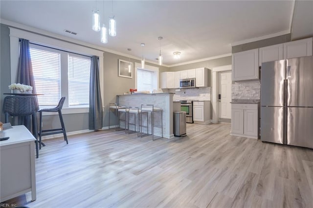 kitchen with a breakfast bar, crown molding, white cabinetry, kitchen peninsula, and stainless steel appliances